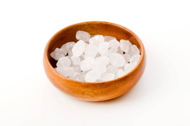 Yuvarlak ahşap bir kasede beyaz arka planda beyaz kaya şekeri