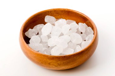 Yuvarlak ahşap bir kasede beyaz arka planda beyaz kaya şekeri