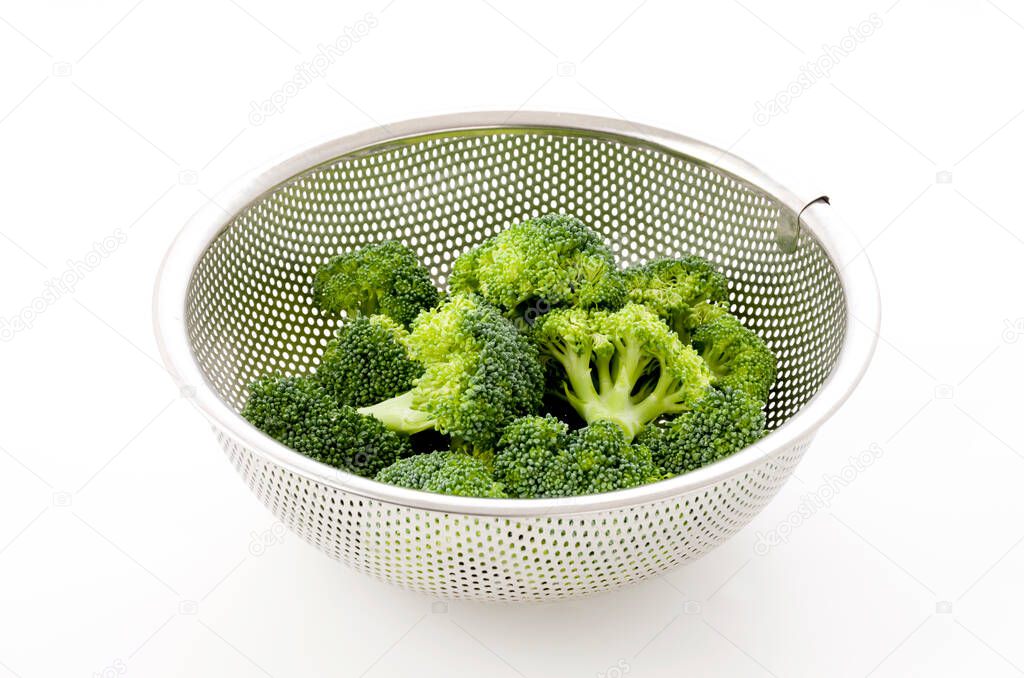fresh broccoli in a stainless steel colander on white background