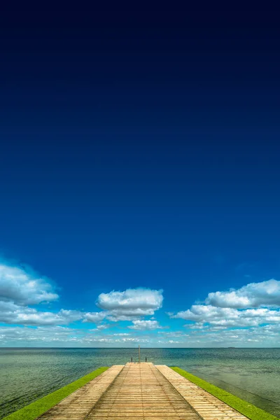 Vieux port de plaisance en bois allant loin à l'horizon de la mer au ciel bleu, summ Images De Stock Libres De Droits