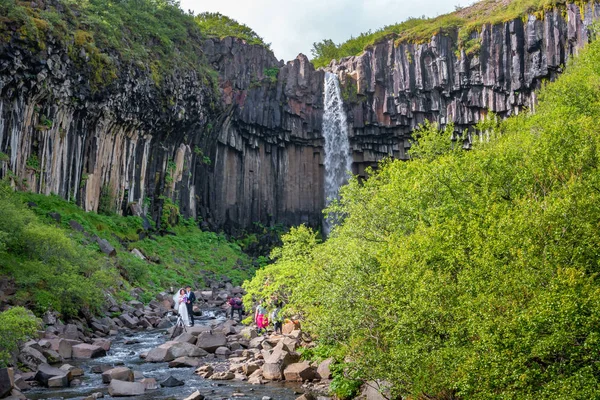 Cerimônia de casamento turístico na cachoeira Svartifoss com ba preto — Fotografia de Stock