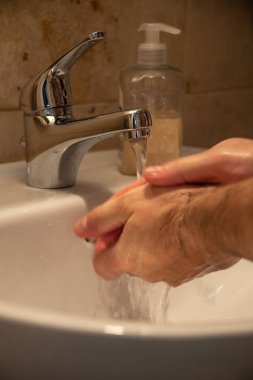 Dünya genelinde koronavirüs salgınını önleme tedbirleri olarak tuvalette sıvı sabunla ellerini yoğun bir şekilde yıkamak, yakın plan.