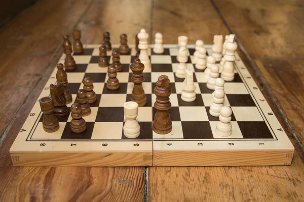 chess on a wooden board set on some wooden floor