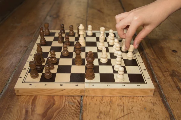 Una sola mano jugando al ajedrez en un tablero de madera — Foto de Stock