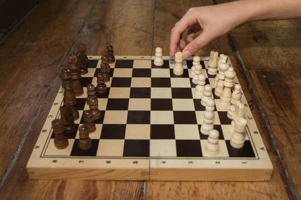 Una sola mano jugando al ajedrez en un tablero de madera — Foto de Stock