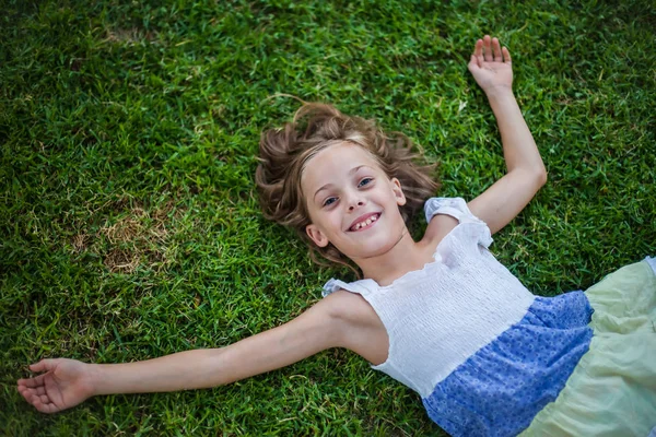 Uśmiechnięta dziewczynka leżąc na trawie — Zdjęcie stockowe