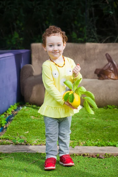 Happy toddler balances lemons — Stock Photo, Image