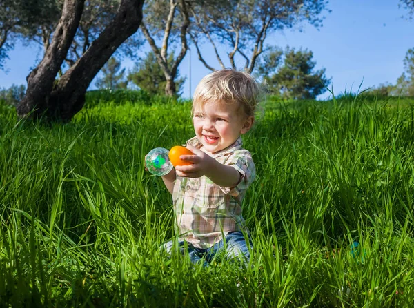 Baby boy holding out an egg — Stock Photo, Image