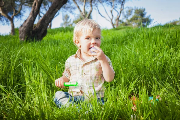 Cute toddler bites an egg — Stock Photo, Image