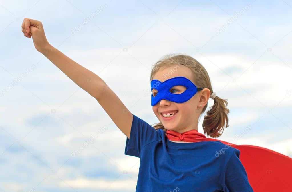Smiling superhero kid against blue sky background.