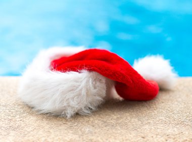 Havuz kenarında kırmızı Noel şapka.