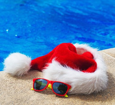 Kırmızı Noel şapka ve güneş gözlüğü havuz yakın. Metin için yer.