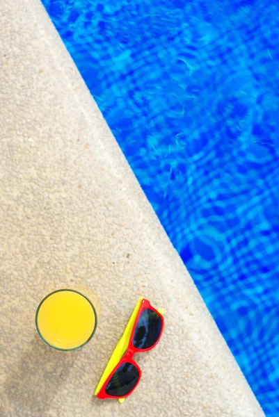 Portakal suyu ve güneş gözlüğü havuz kenarında. Metin için yer. — Stok fotoğraf