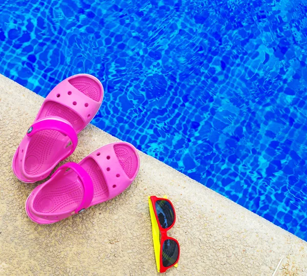 Pantofle a sluneční brýle u bazénu. Prostor pro text. — Stock fotografie
