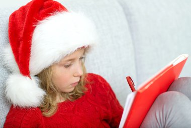 Noel Baba'ya bir mektup yazma kırmızı şapkalı küçük kız.