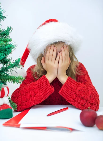 Sad little girl in red hat writing a letter to Santa Claus. — Stock Photo, Image