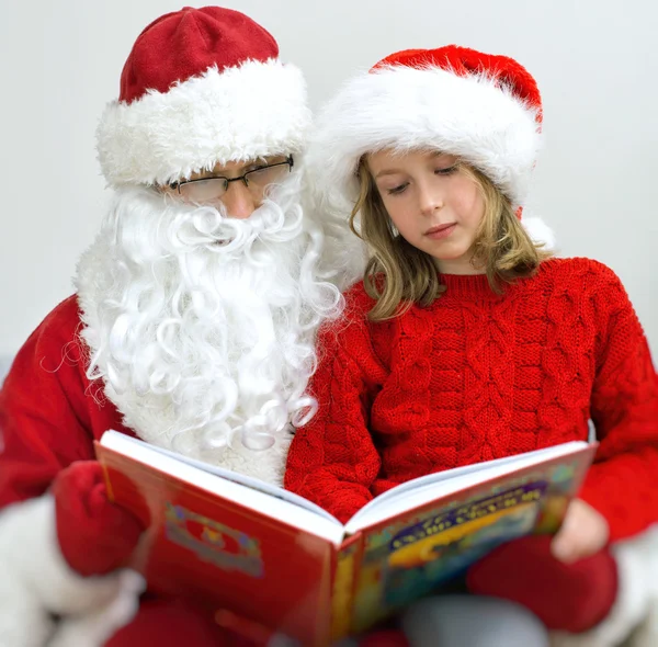 Kerstman en meisje het lezen van sprookjes met Kerstmis. — Stockfoto