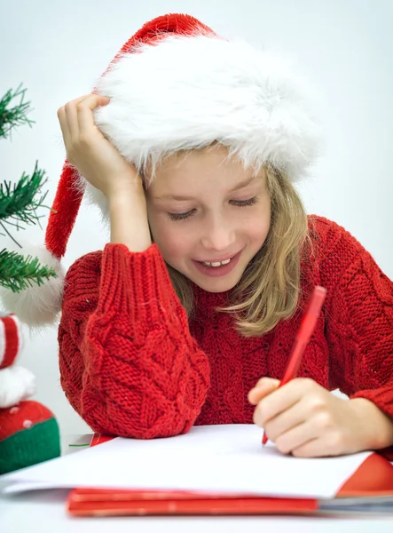 Bonne petite fille au chapeau rouge écrivant une lettre au Père Noël . — Photo