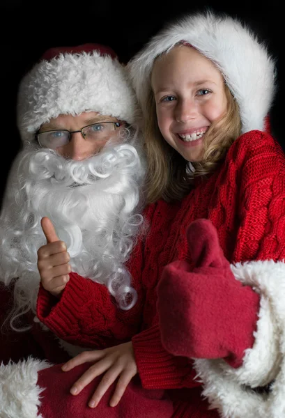 Happy little girl with Santa Claus showing thumbs up. — Stock Photo, Image