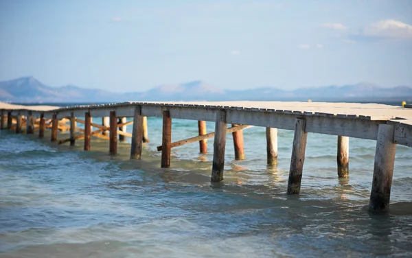 Stare drewniane molo prowadzące do morza. — Darmowe zdjęcie stockowe