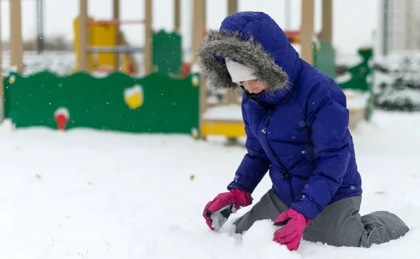 Little girl rolling snowball in winter. — Stock Photo, Image