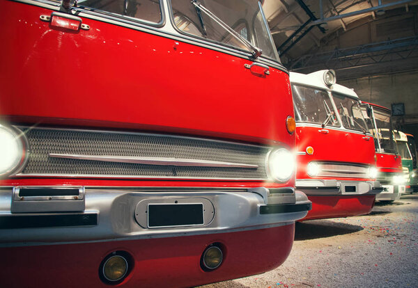 Many red city buses in depot.