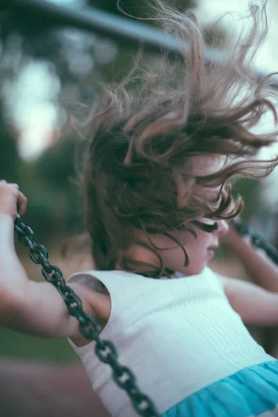 Uma menina a balançar no parque. Em movimento . — Fotografia de Stock