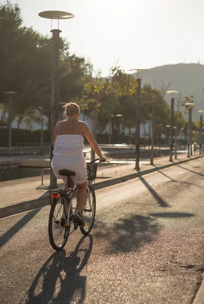 Žena cyklista jedoucí na kole na ulici při západu slunce. — Stock fotografie