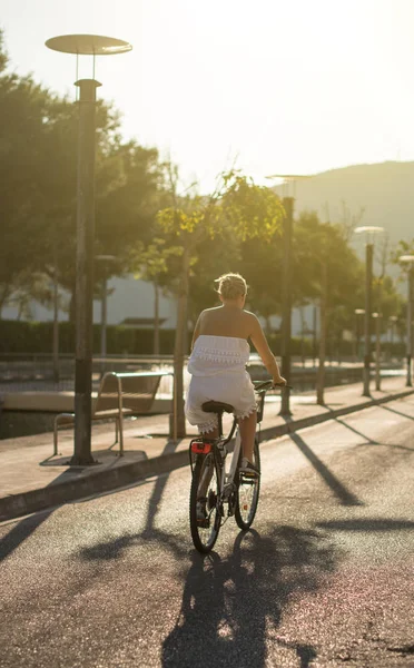 Žena cyklista jedoucí na kole na ulici při západu slunce. — Stock fotografie