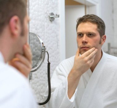 Sakalını seyir ve tıraş hakkında düşünme bir adam.