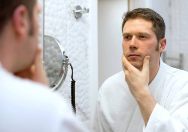 Sakalını seyir ve tıraş hakkında düşünme bir adam.