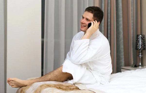 Szczęśliwy człowiek w szlafrok z telefonu w pokoju hotelowym. — Zdjęcie stockowe