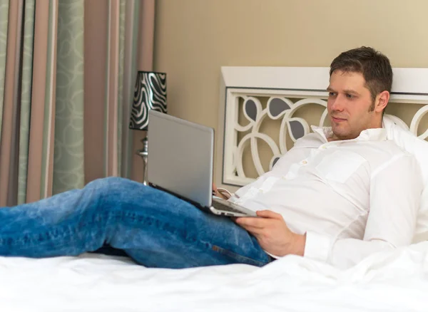 Hombre guapo usando portátil en la habitación de hotel . — Foto de Stock