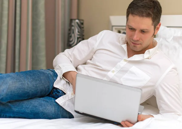 Hombre guapo usando portátil en la habitación de hotel . — Foto de Stock