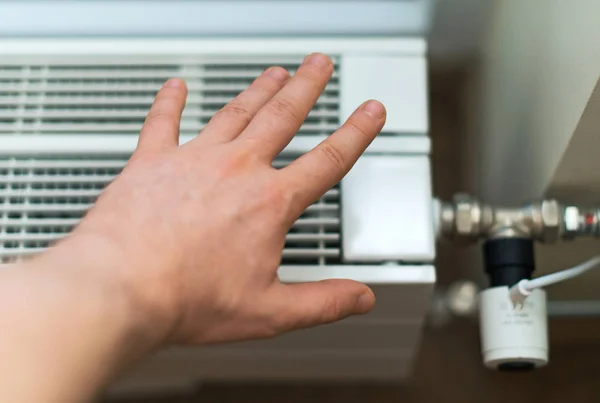 Man's hand checking temperature of heating radiator.