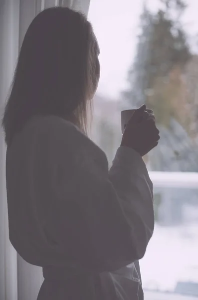 Mujer disfrutando de su café de la mañana cerca de la ventana . —  Fotos de Stock