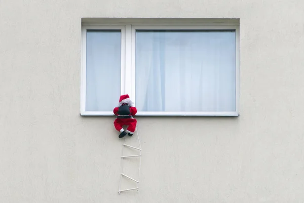 Brinquedo Papai Noel escalando na parede . — Fotografia de Stock