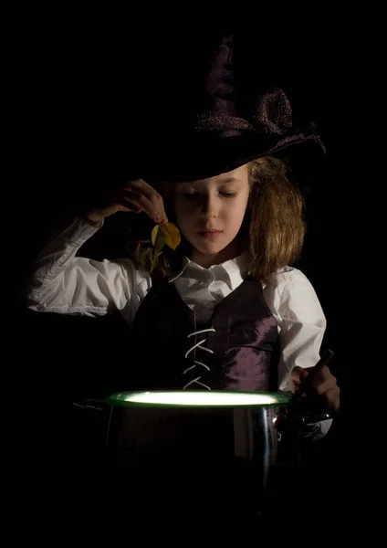 Malá holčička v kostýmu čarodějnice připravuje lektvar. — Stock fotografie
