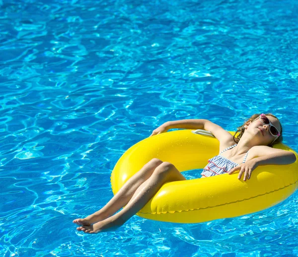 Liten flicka med uppblåsbar gummiring avkopplande i poolen. Plats för text. — Stockfoto