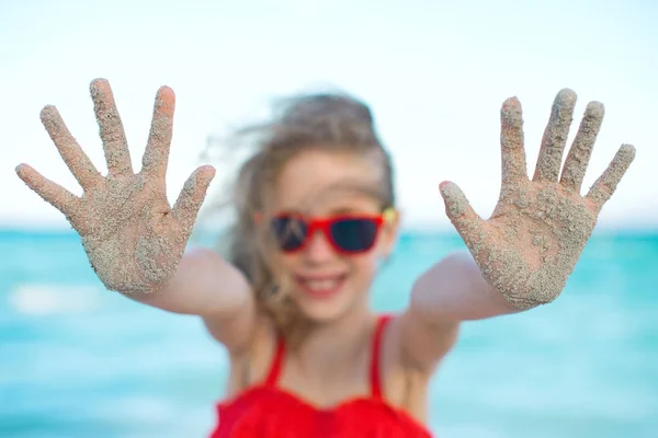Sommar semester koncept. Leende flicka visar händer i sanden. — Stockfoto