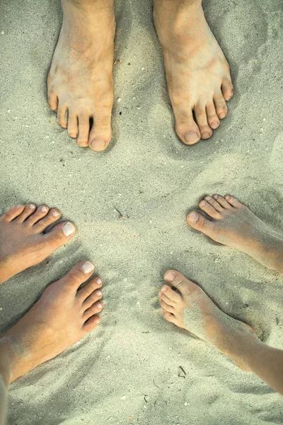 Tres pares de pies en la arena. Vista superior . — Foto de Stock