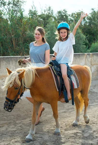 Woman leading pony with little girl. — Stock Photo, Image