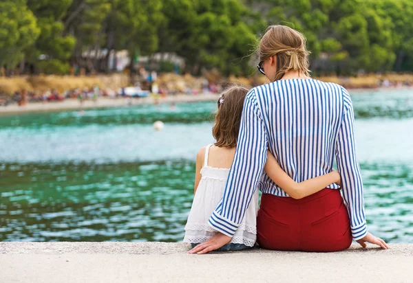 Little girl with mother sitting on the pier. — Stock Photo, Image