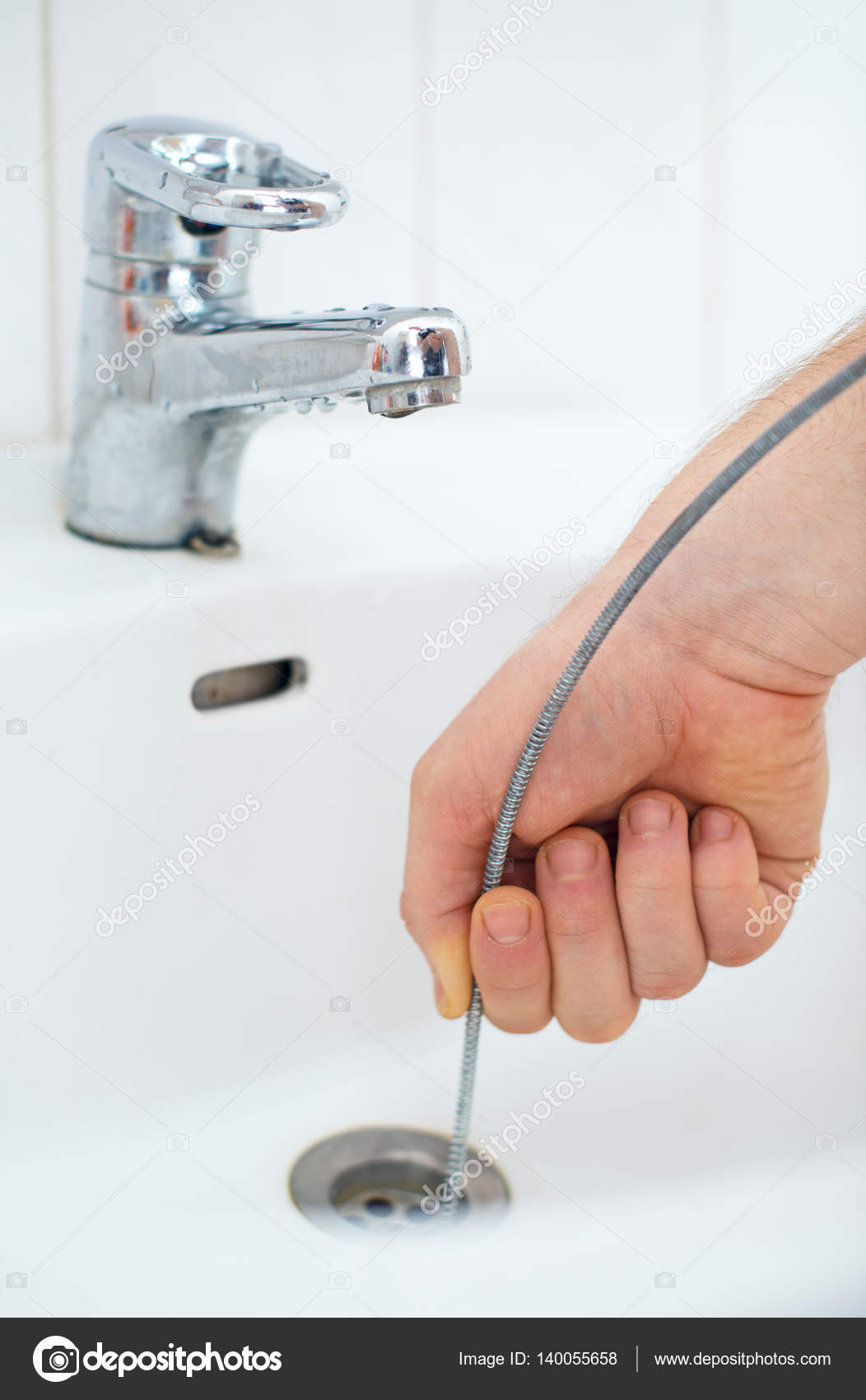 Plumber using drain snake to unclog bathtub., Stock image