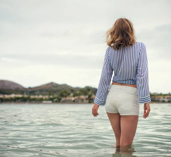 Jeune femme debout dans la mer. Par derrière. . — Photo