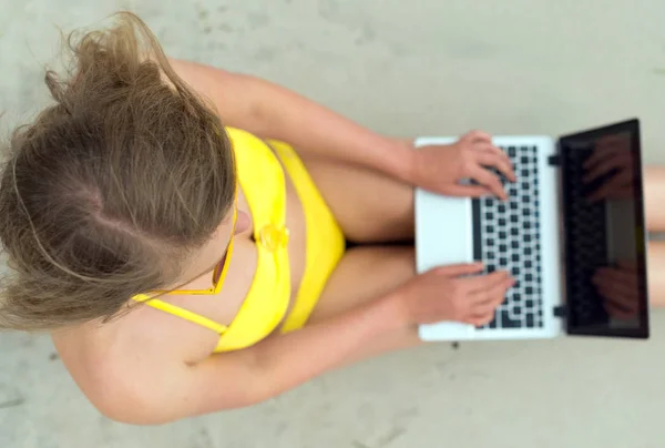女孩在沙滩上笔记本电脑上工作。顶视图. — 图库照片