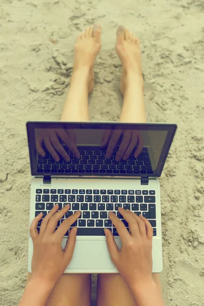 Une fille qui travaille sur un ordinateur portable sur la plage. Vue du dessus . — Photo