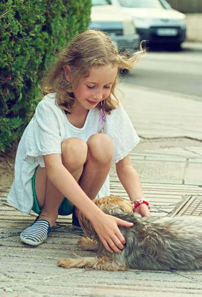 Cute little girl with stray dog on the street. — Stock Photo, Image