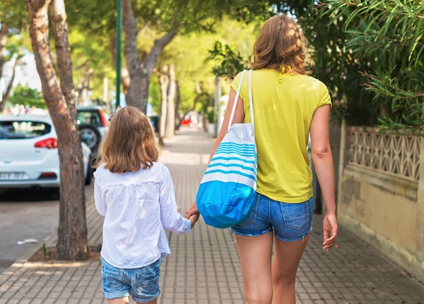 Маленька дівчинка і її мати йдуть по вулиці . — стокове фото