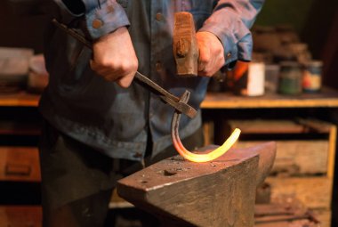 At nalı yapımında. Erkek işçi pense ve at nalı yapma çekiç ile.